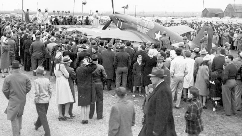 A crowd gathers around the Spirit of Universal fighter plane.