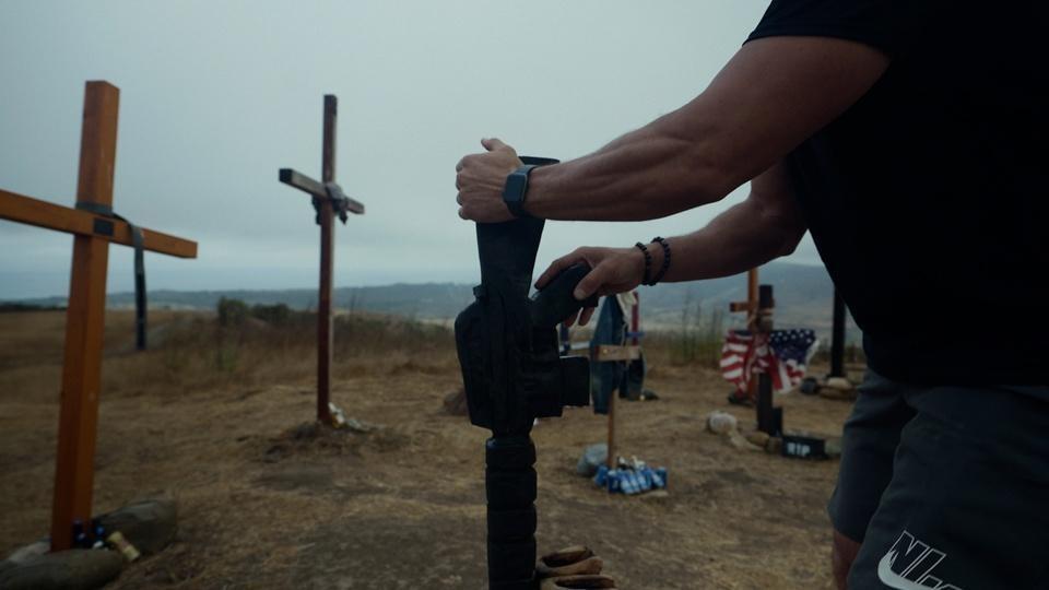 A soldier stands in a graveyard of handmade crosses.