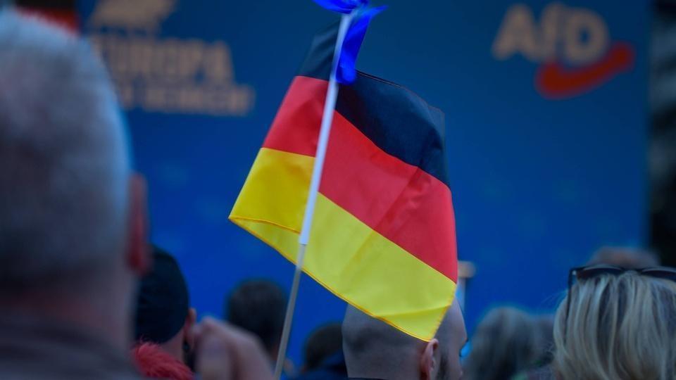 A small German flag held up in a crowd at a political rally.