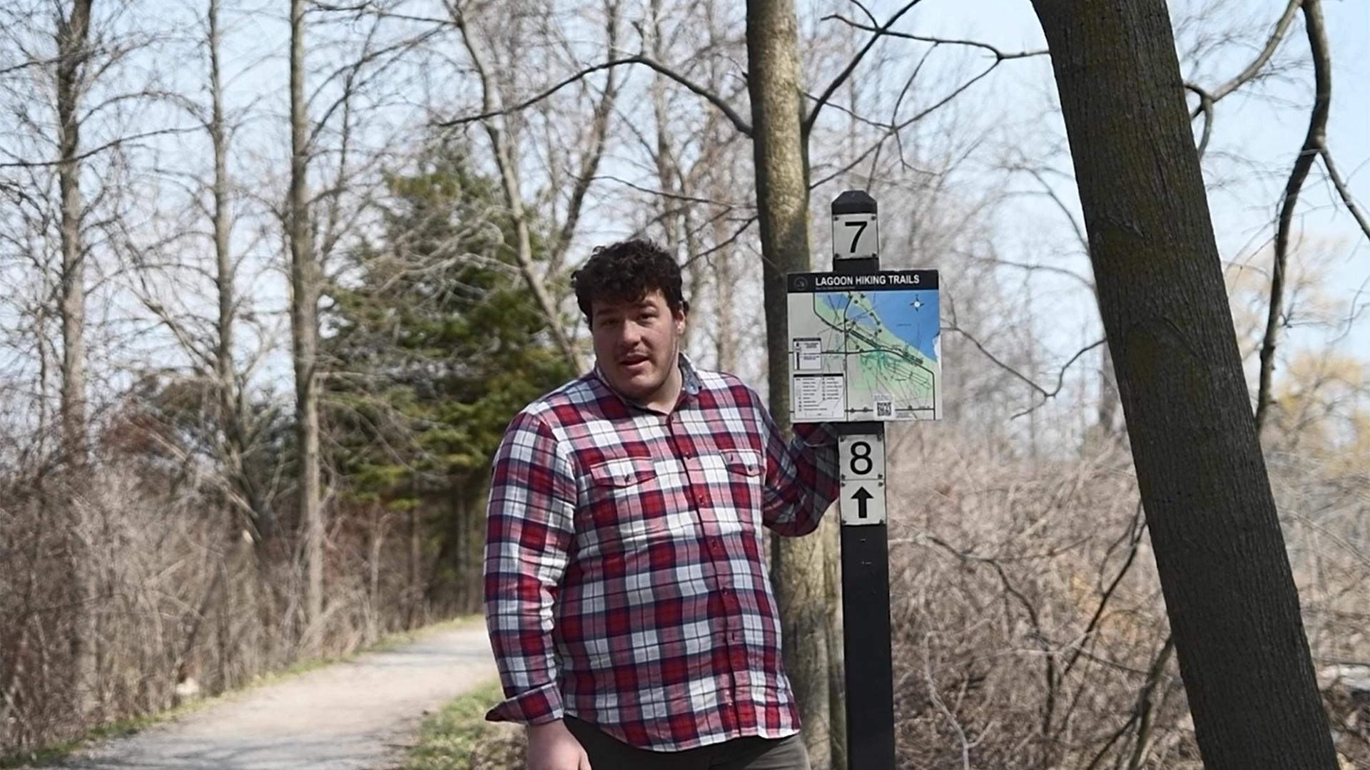 Brett Russell at a sign for Bay City State Park's lagoon hiking trails.