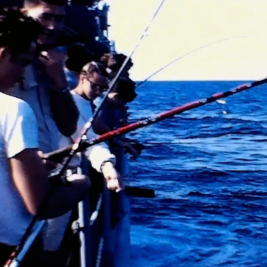 Sailors fishing off the side of the Edson.