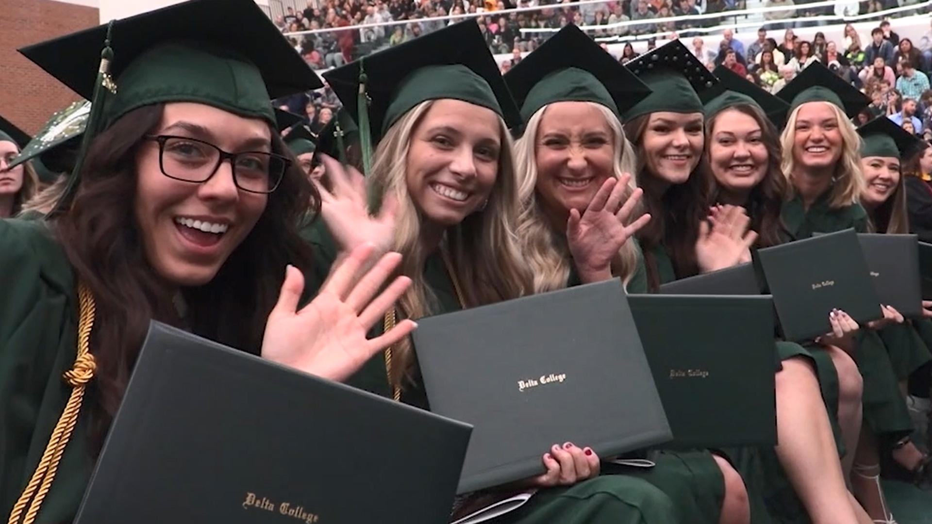 Delta College graduates waving at the camera.