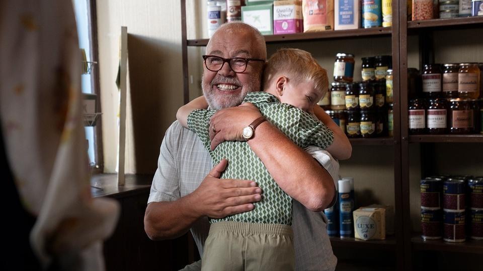 A man and boy hug joyfully.