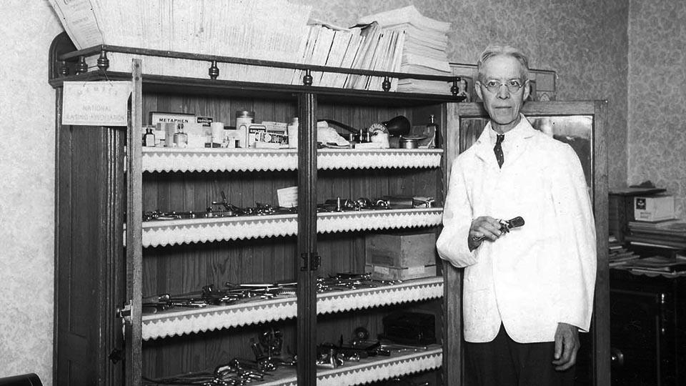 Dr. Wilke Drake stands next to a cabinet full of surgical equipment.