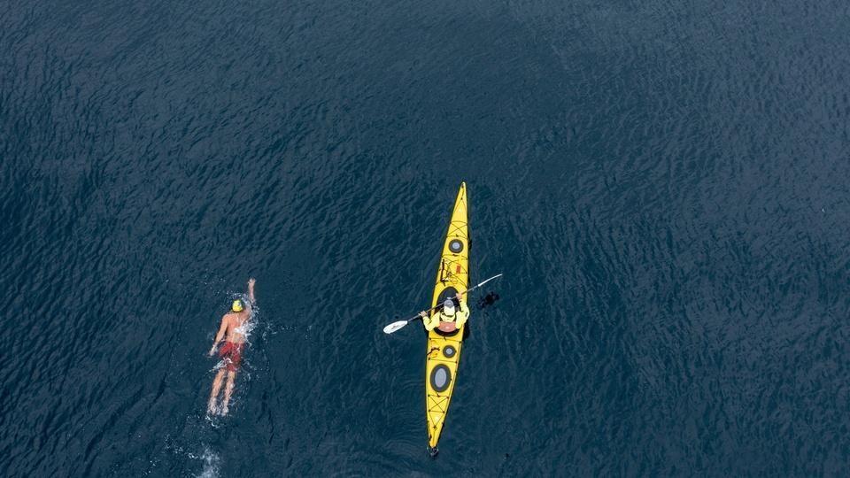 A person swimming and a person kayaking in Lake Superior.
