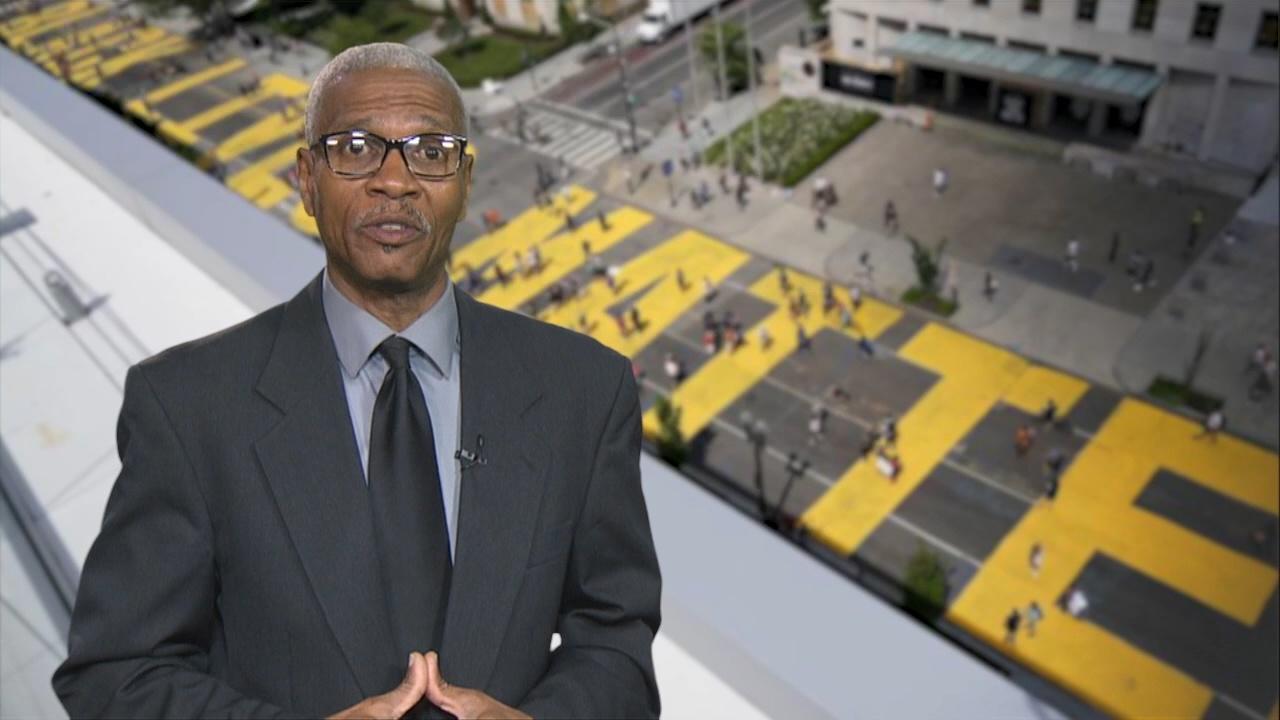 Host Darold Newton standing in front of Black Lives Matter painted on a Washington, DC street.