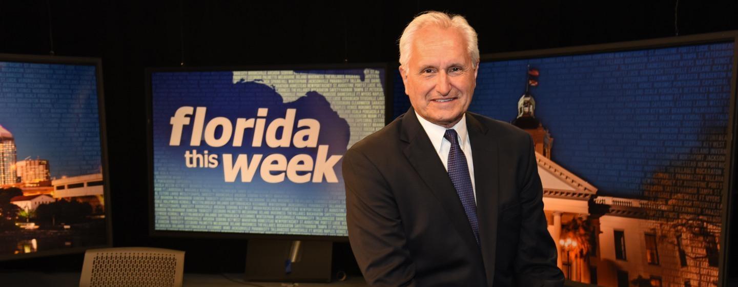 Rob Lorei seated on the desk of the Florida This Week set at WEDU PBS