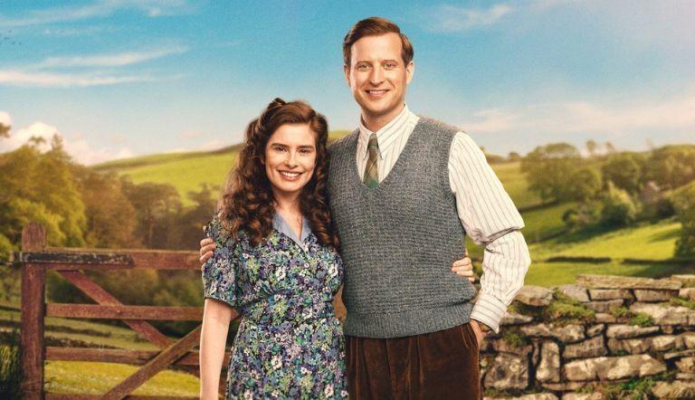 James Herriot and Helen Herriot facing the camera, embracing in front of a pastural dale.