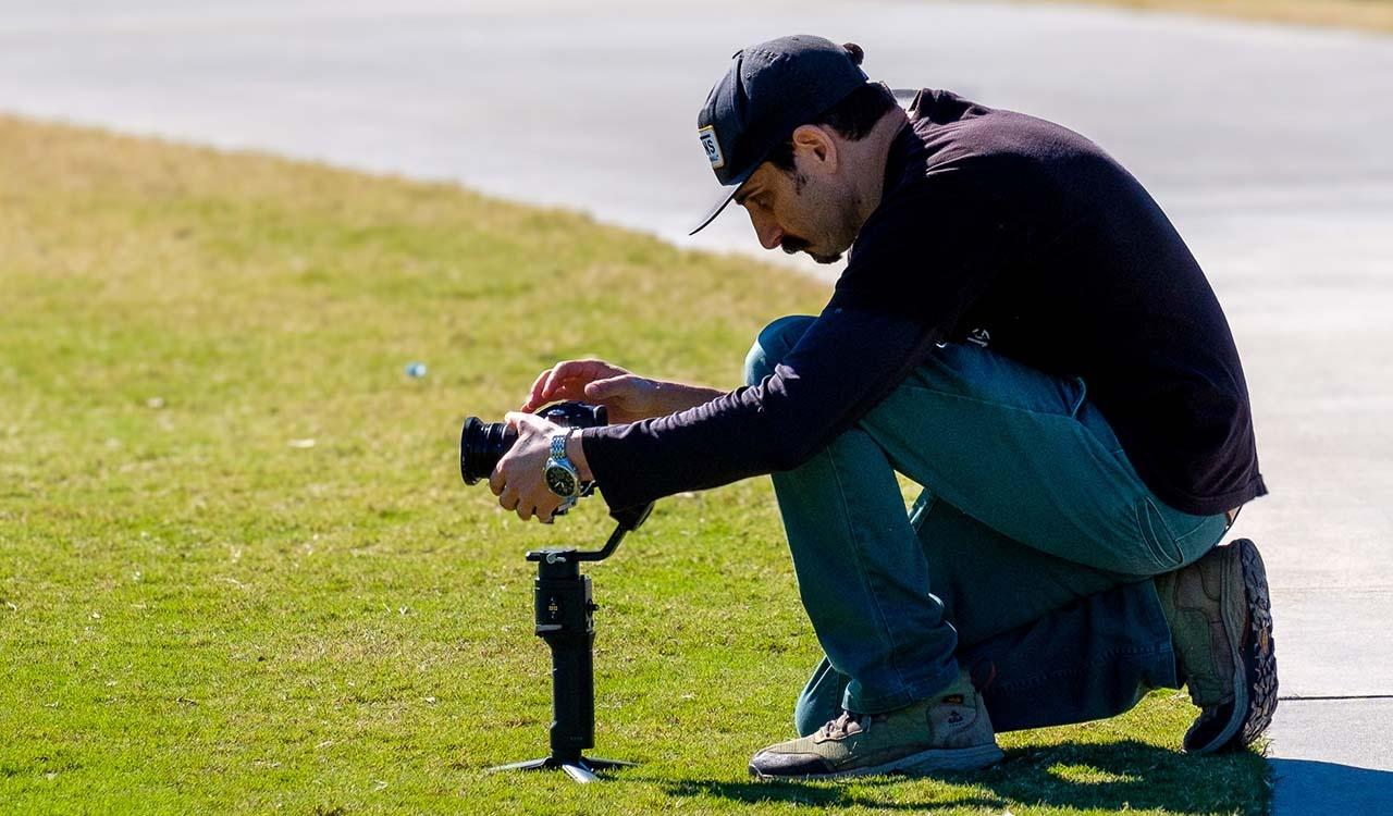 Triforce camera man setting up a camera on a green lawn