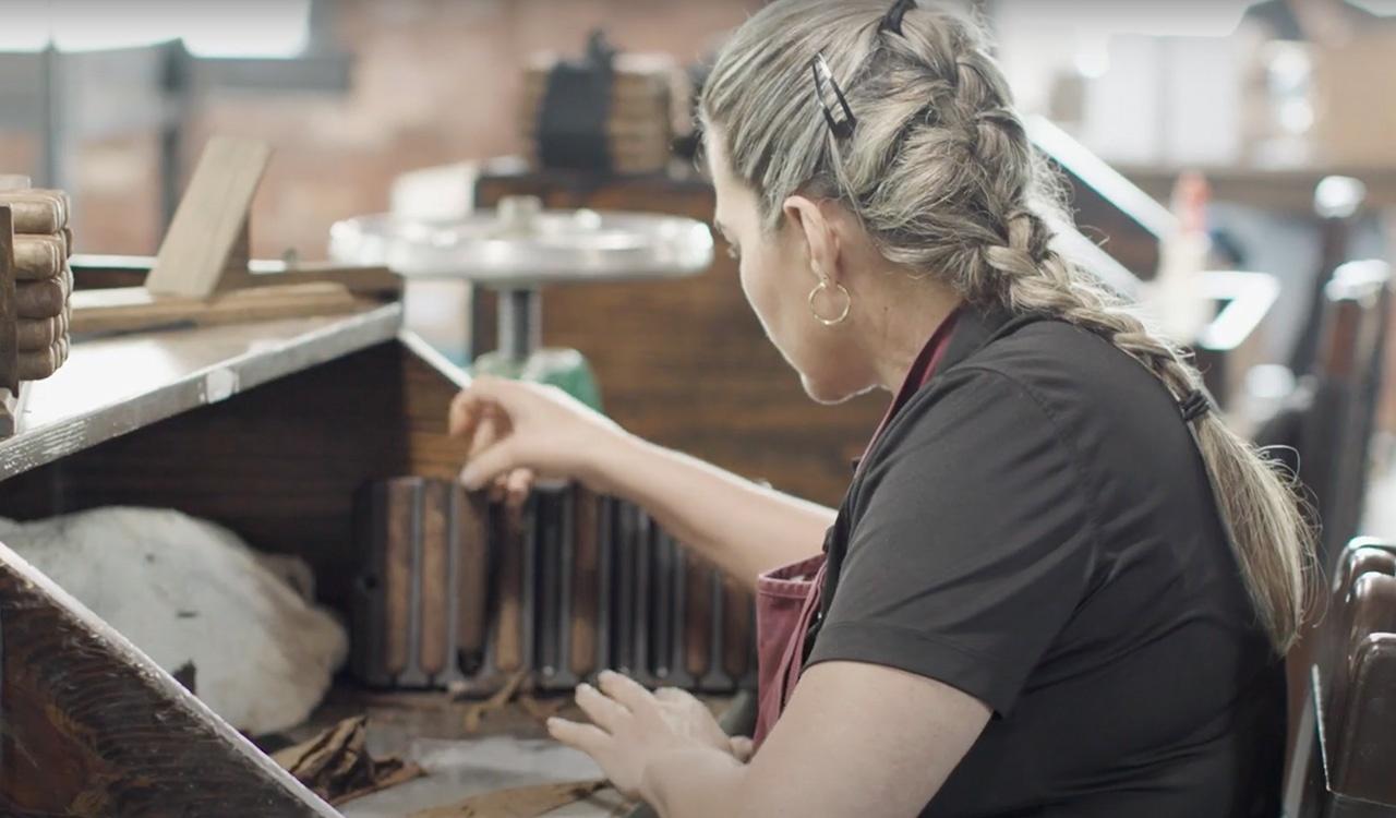 Woman at her station, hand rolling cigars