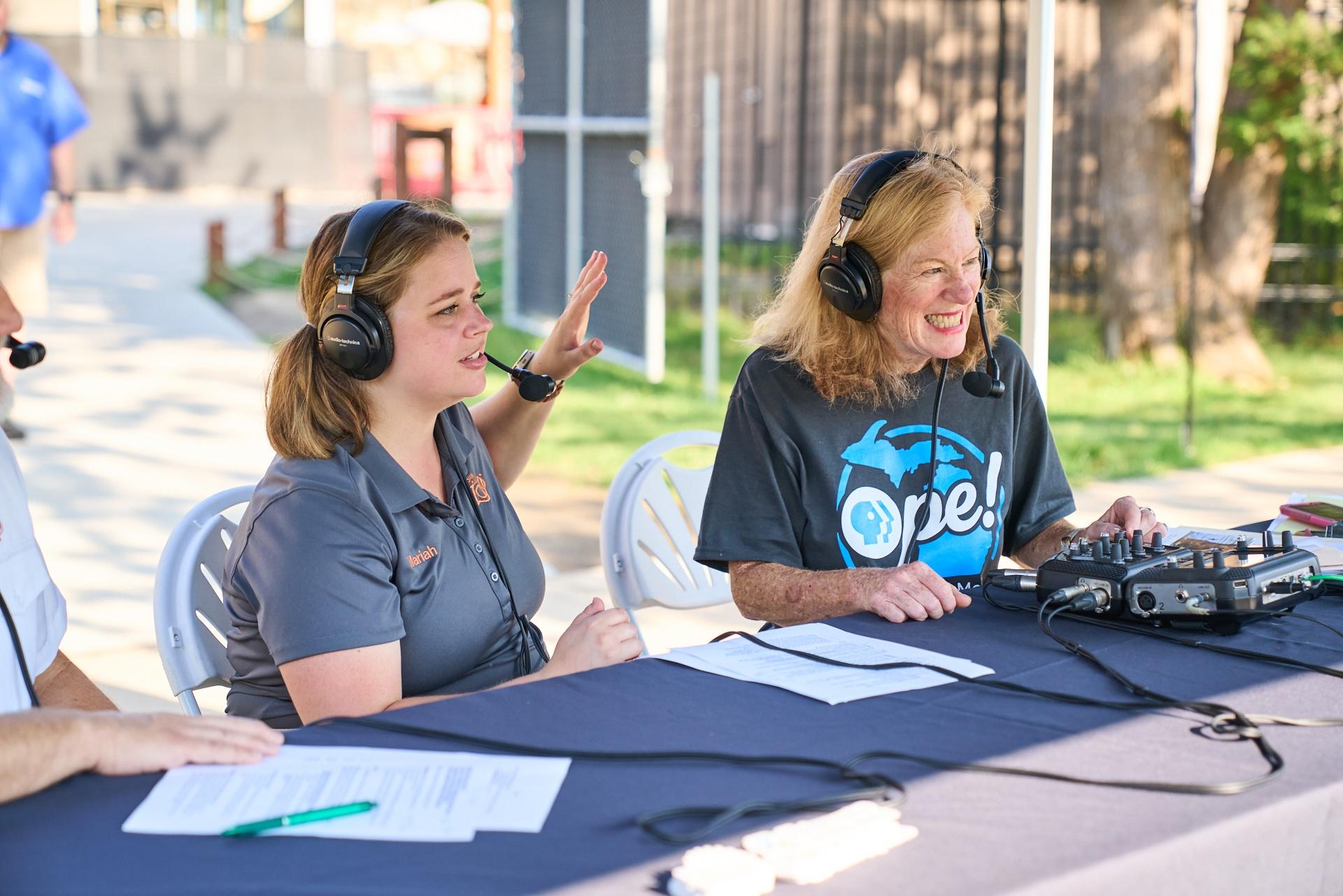 Shelley Irwin and a John Ball Zoo employee smile while talking into headsets during a recording session at KidsDay at the Zoo