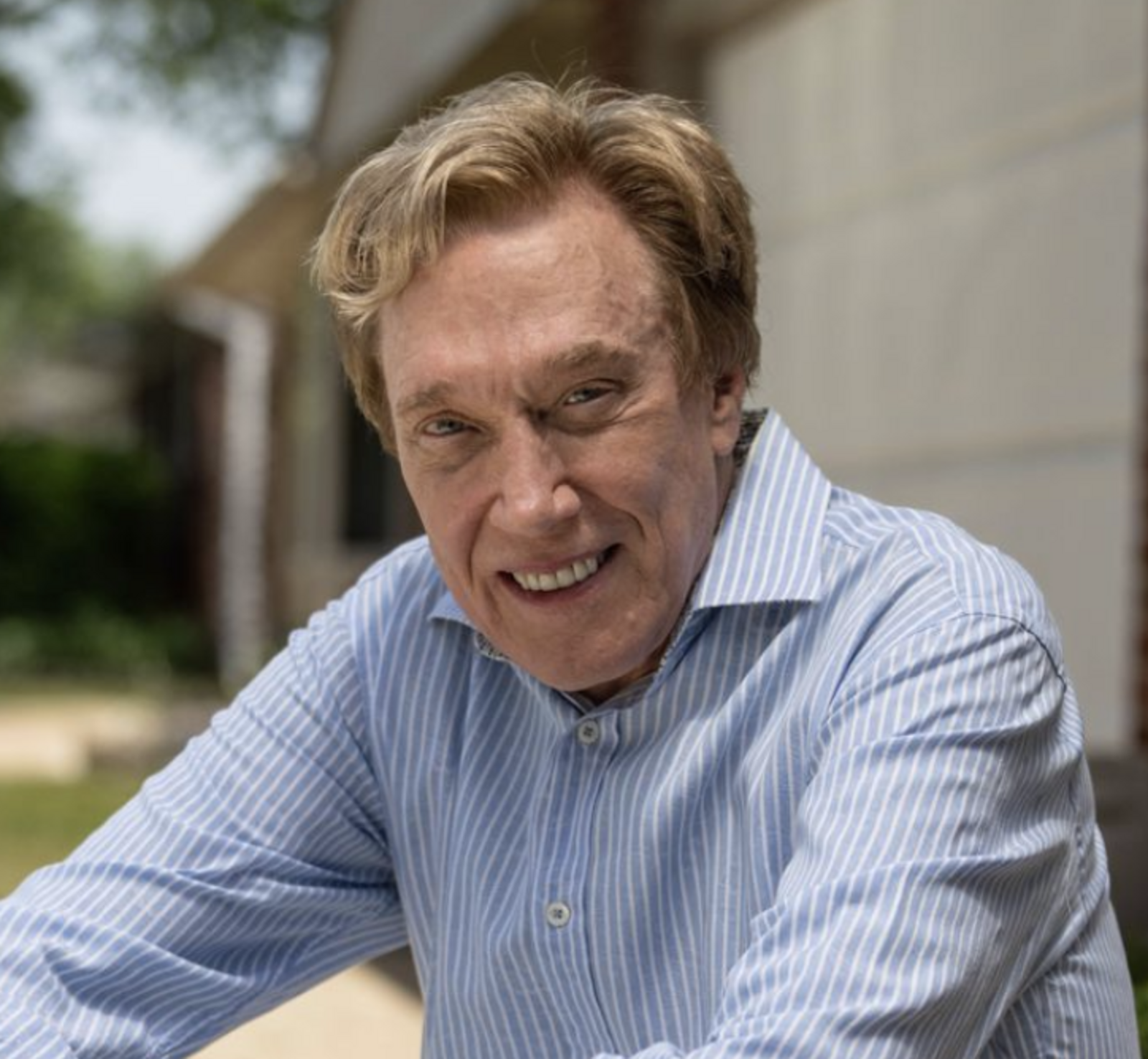 perry johnson smiles at the viewer wearing a blue button down shirt