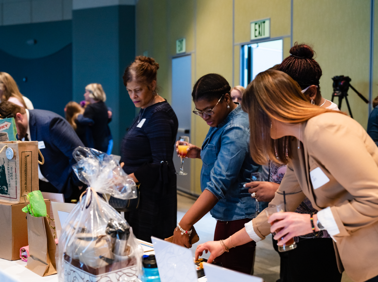 Individuals discussing various baskets of items and prizes at an event