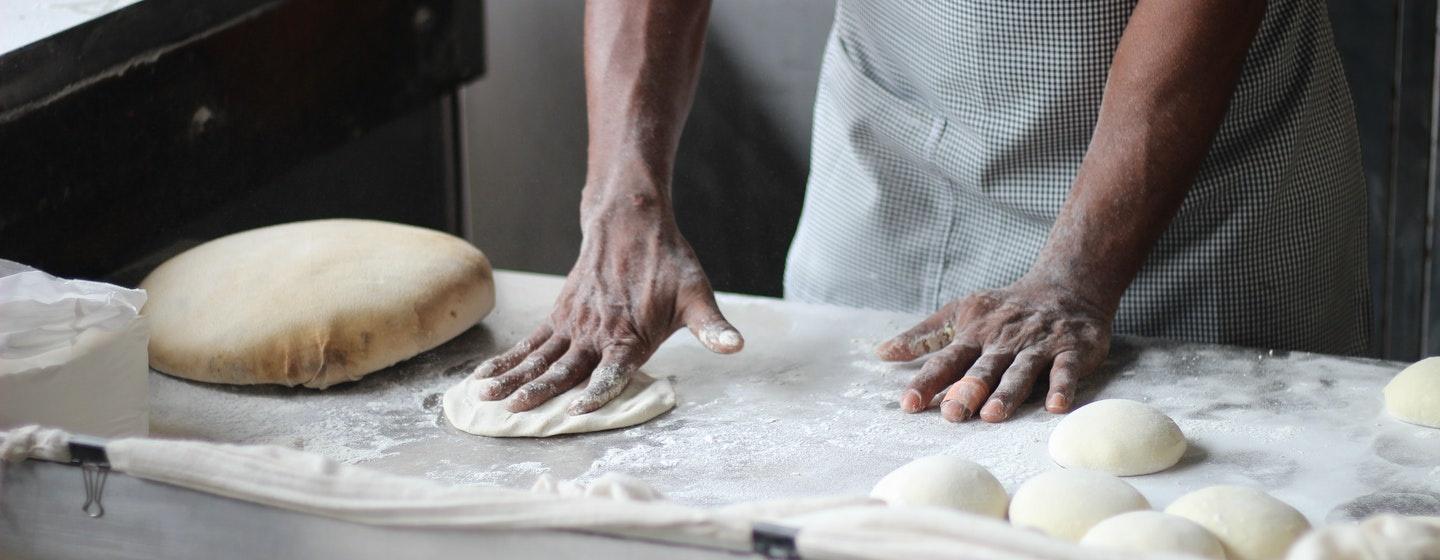 Hands work with dough in a kitchen