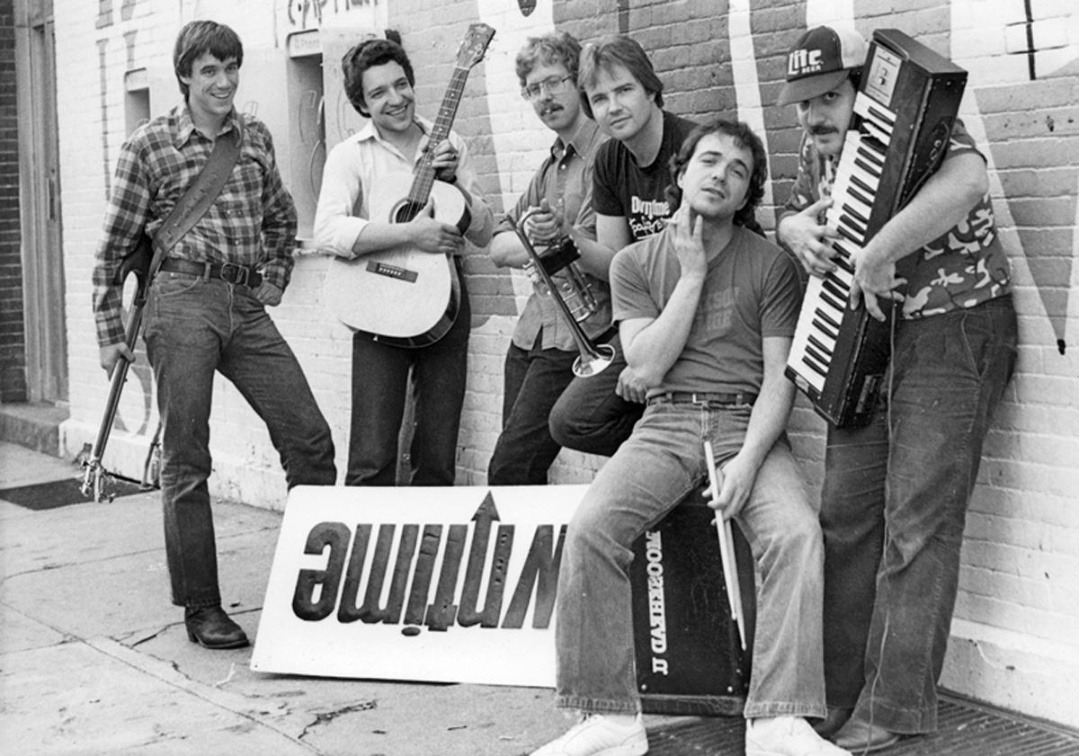 A black and white photo of the band Downtime standing and leaning against a brick wall.