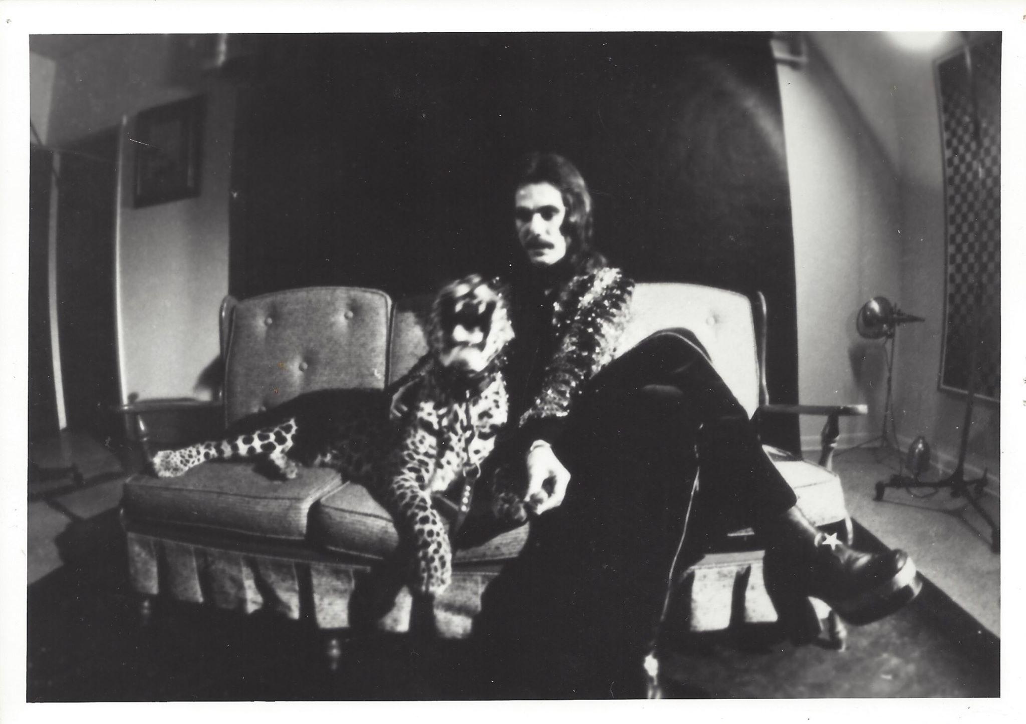 A black and white photo of the Hullabaloo resident leopard named Tanya sitting to the right of musician Joe Mele.