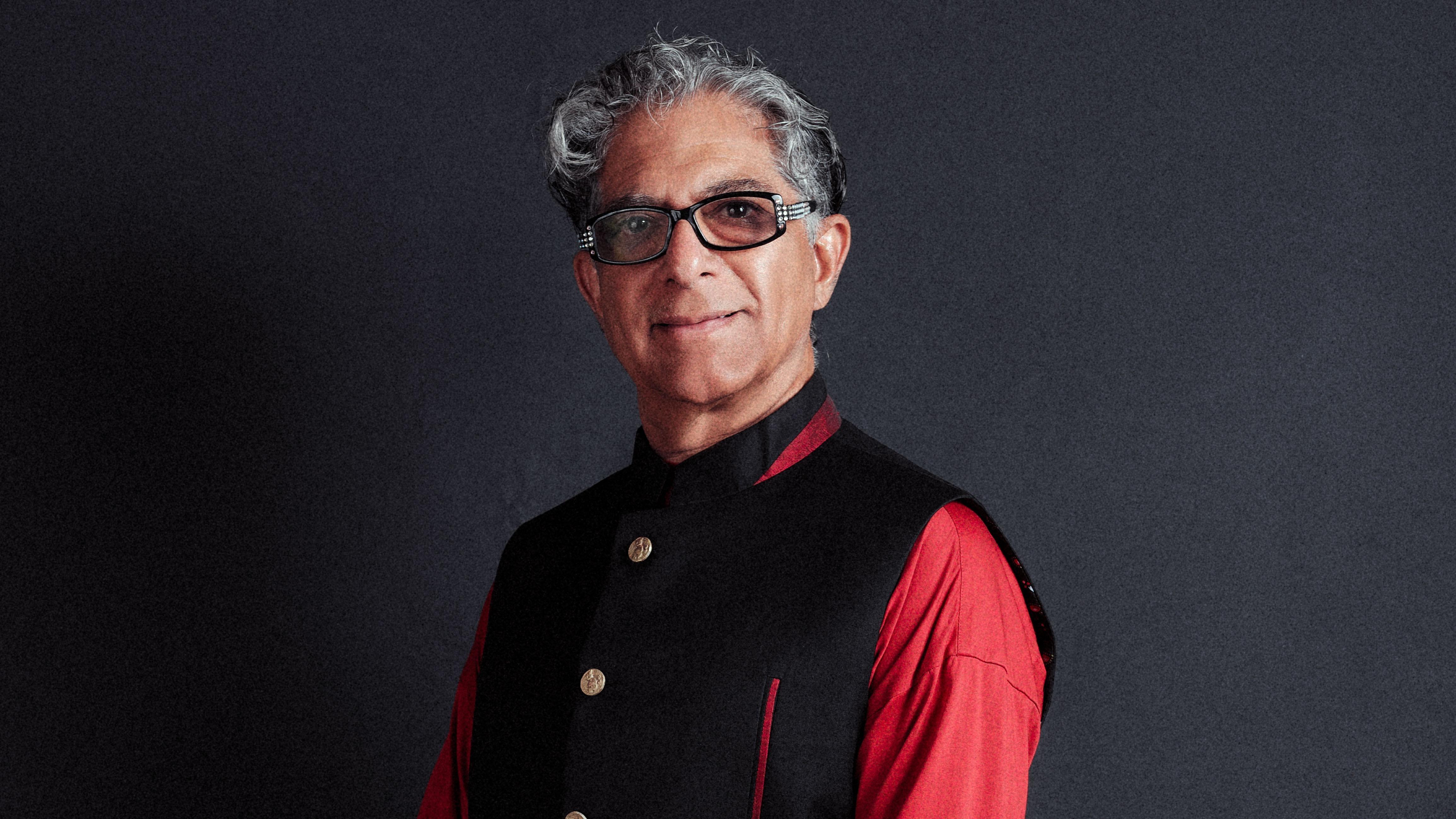 Deepak Chopra smiling on a gray background