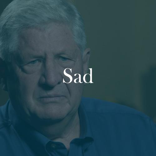The word "sad" is displayed in white, serif, type on a dark green overlay over an image of Roy.