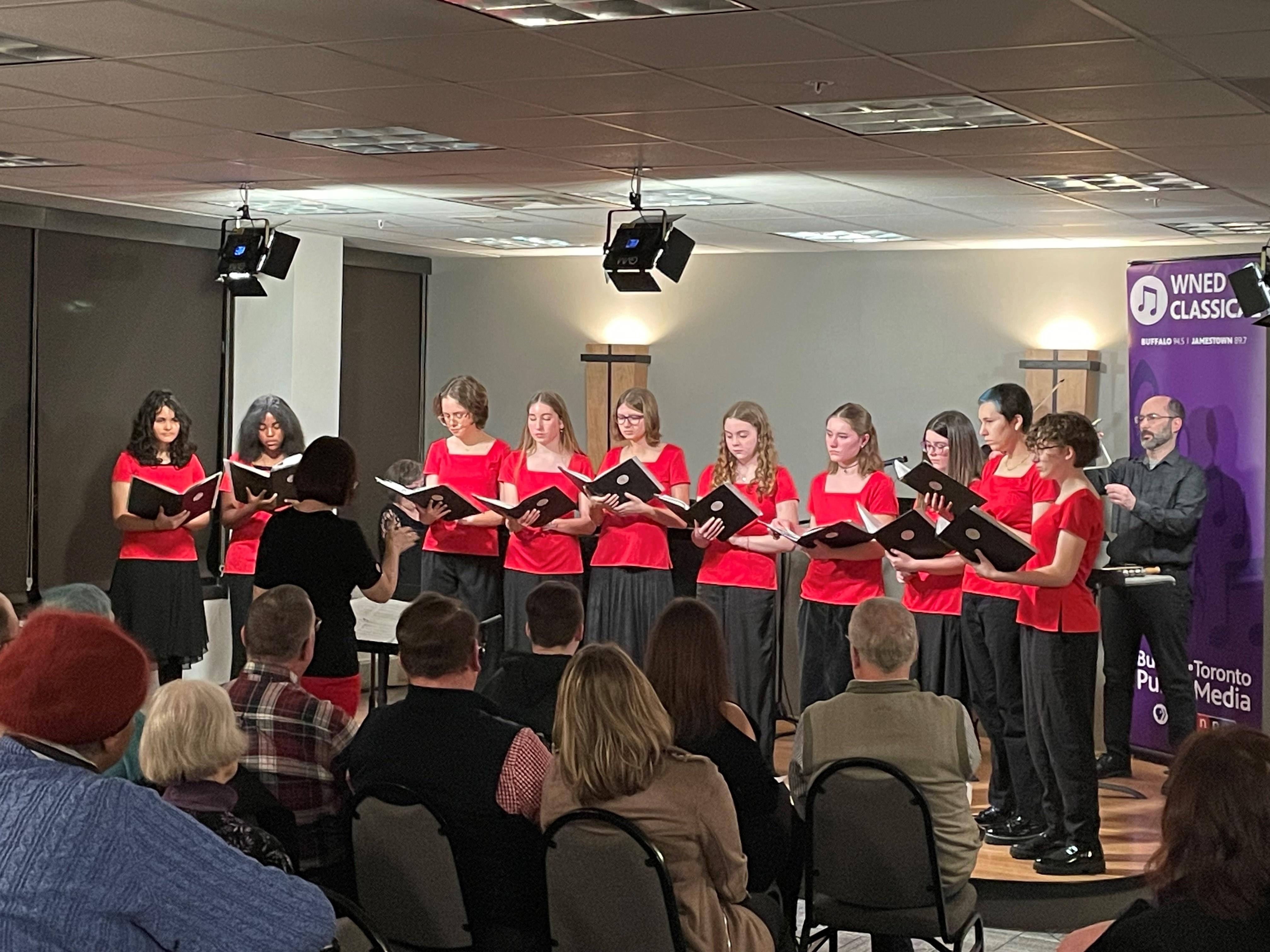 Buffalo Girl Choir (all wearing red shirts and black bottoms) performing onstage