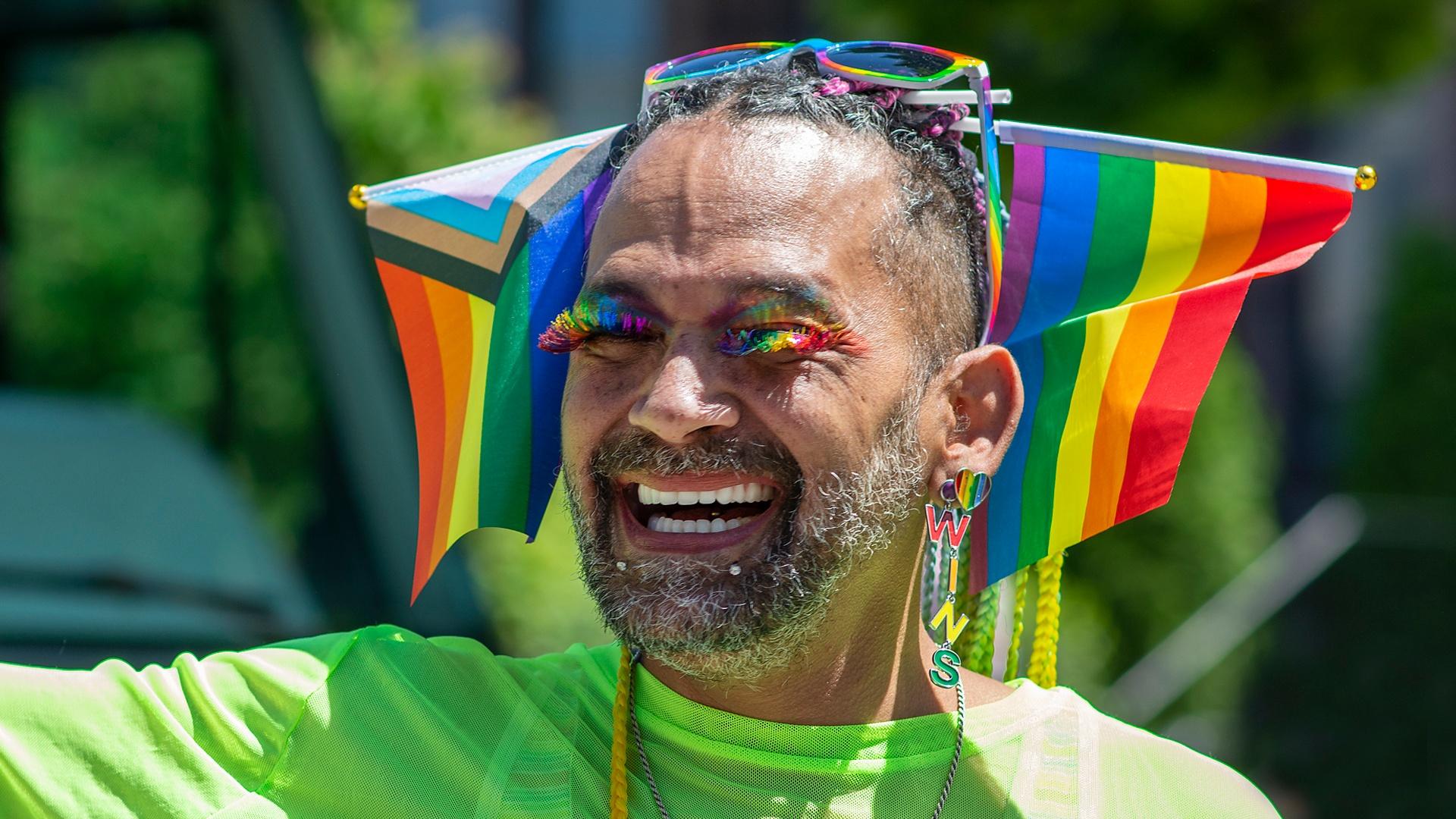 man with rainbow eyelashes smiles 