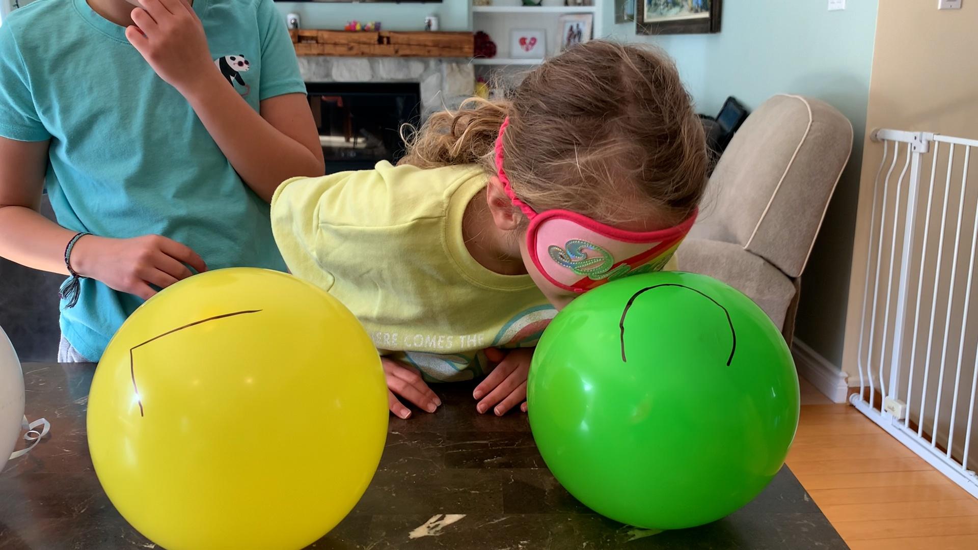 young girl, blindfolded, smelling a balloon