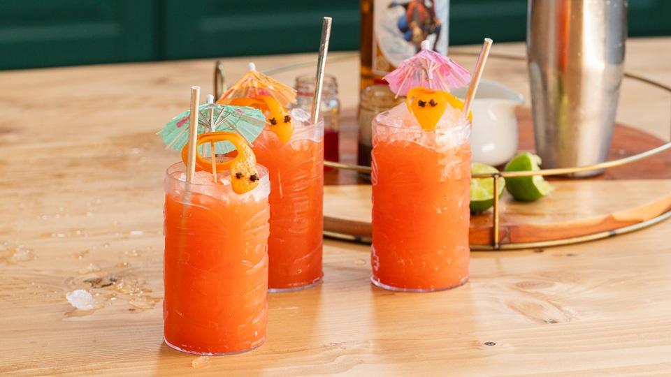 Orange summer drinks topped with a "snake" made from an orange peel and a paper drink umbrella
