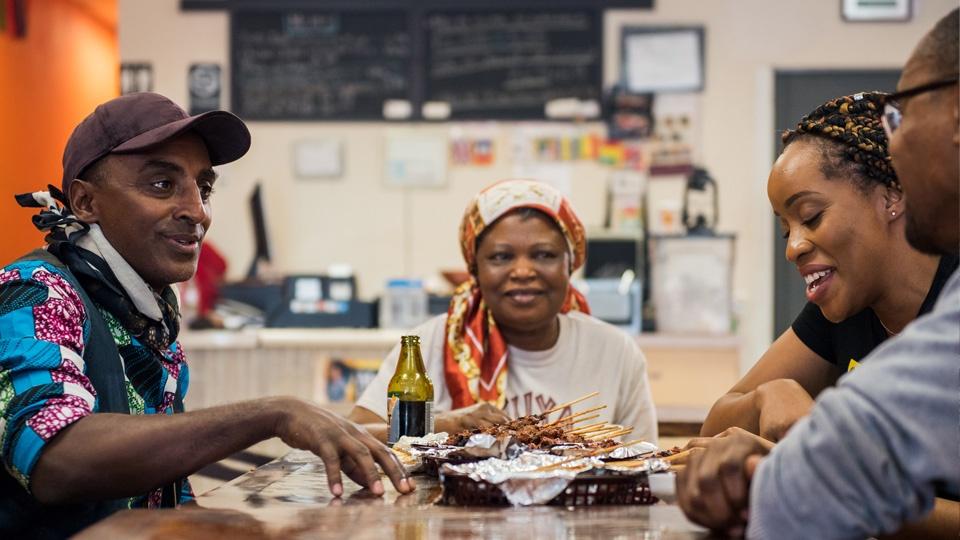 A black family gathered around a dinner table in a happy discussion