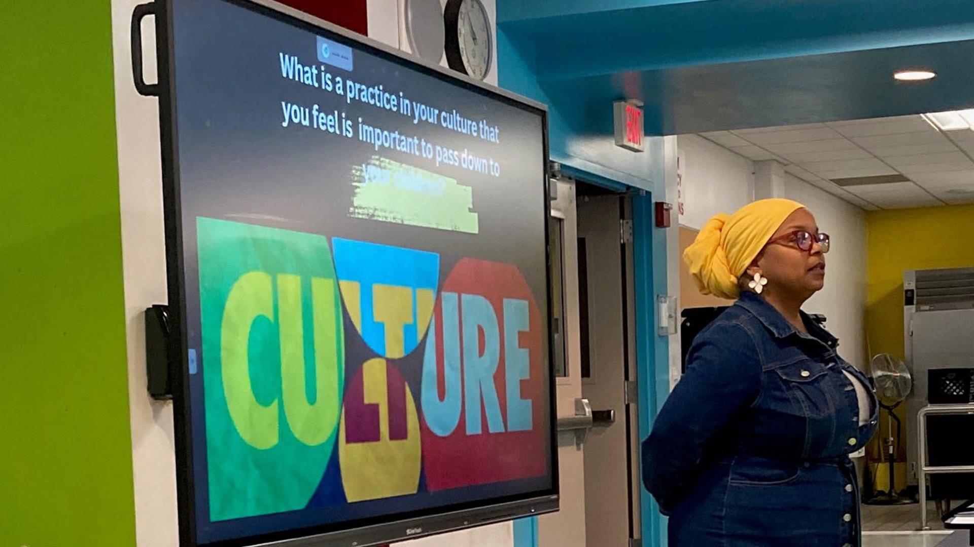 Woman  standing in front of a screen that reads "CULTURE"