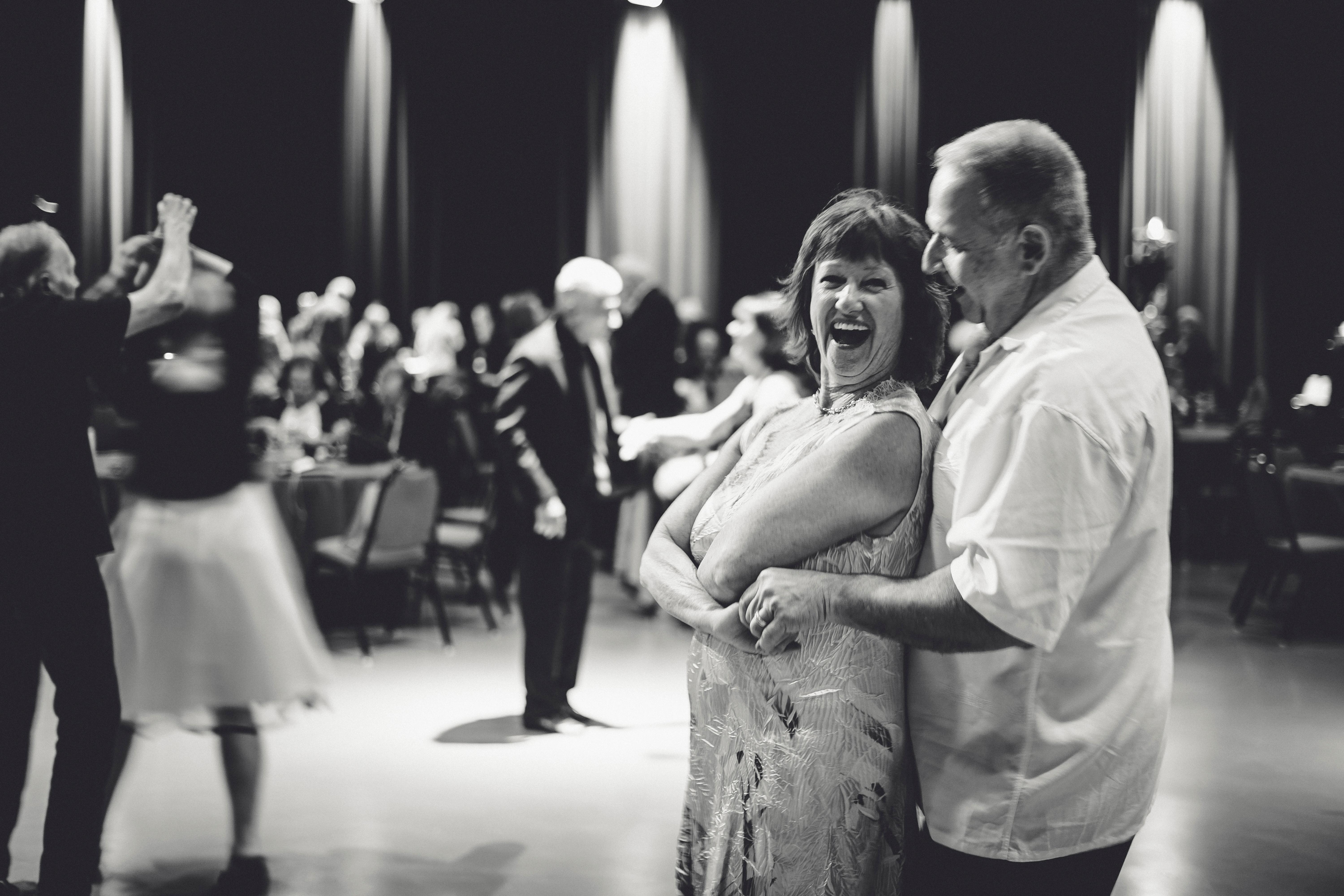 A black and white image of a woman smiling while dancing with her male significant other