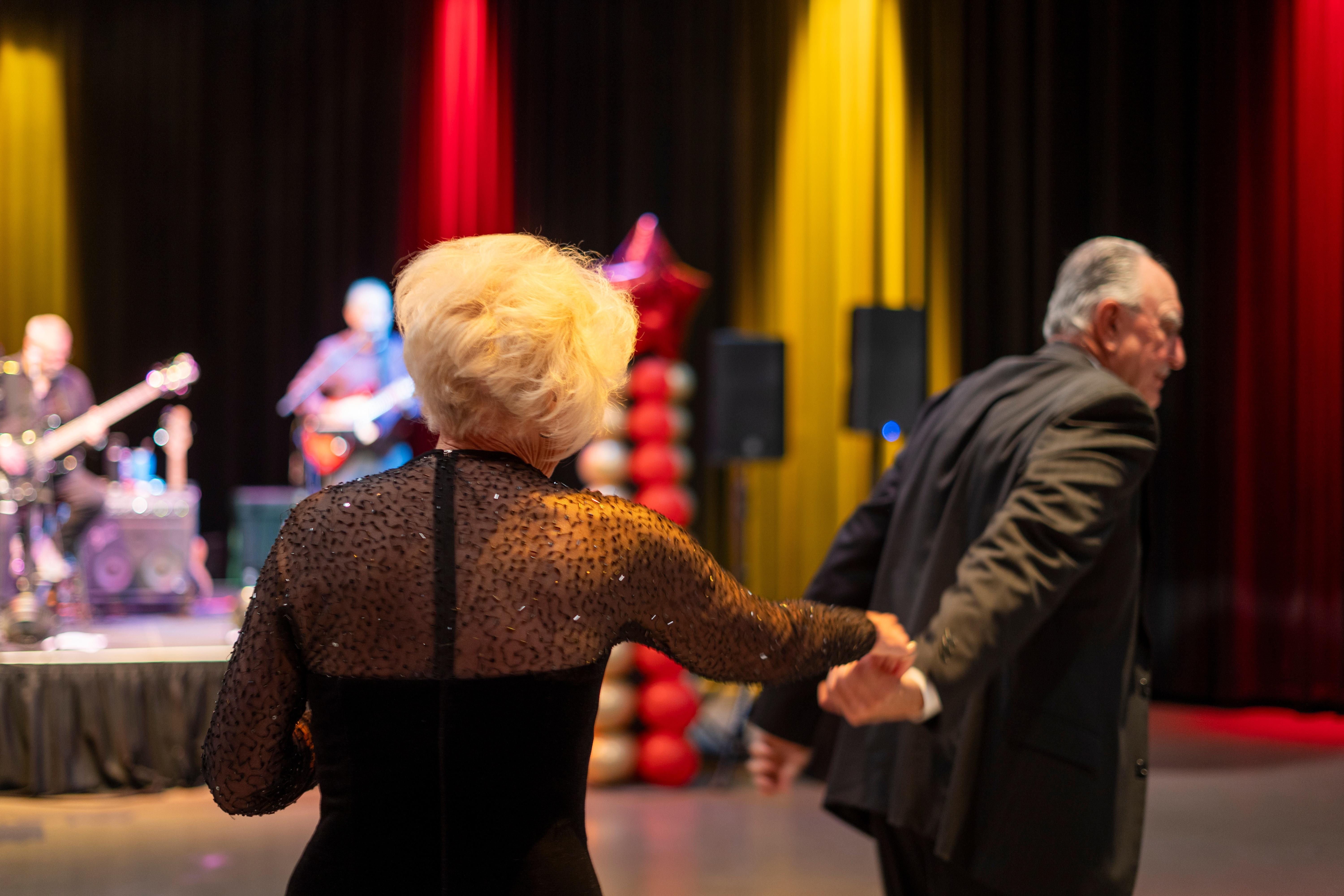 A man leading a woman onto the dancefloor at BTPM's Senior Prom