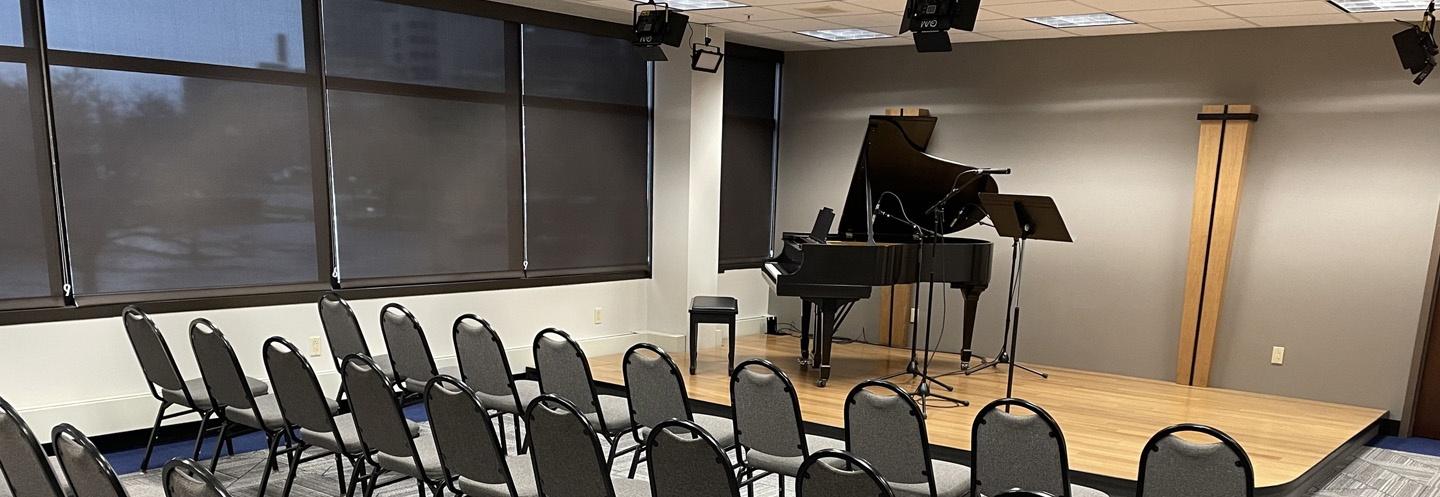 BTPM Performance space with rows of chairs and a grand piano on stage