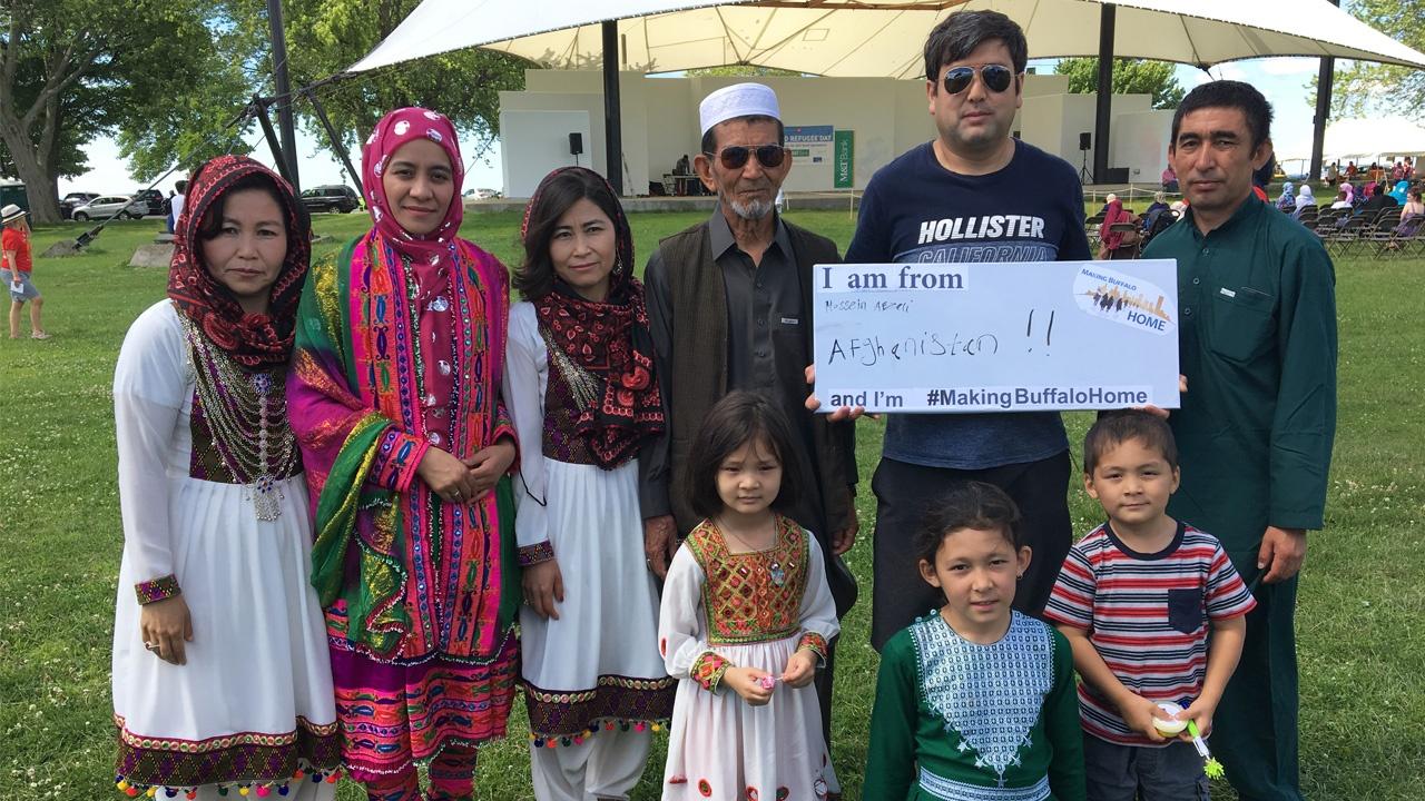 Family from Afghanistan holding a Making Buffalo Home sign