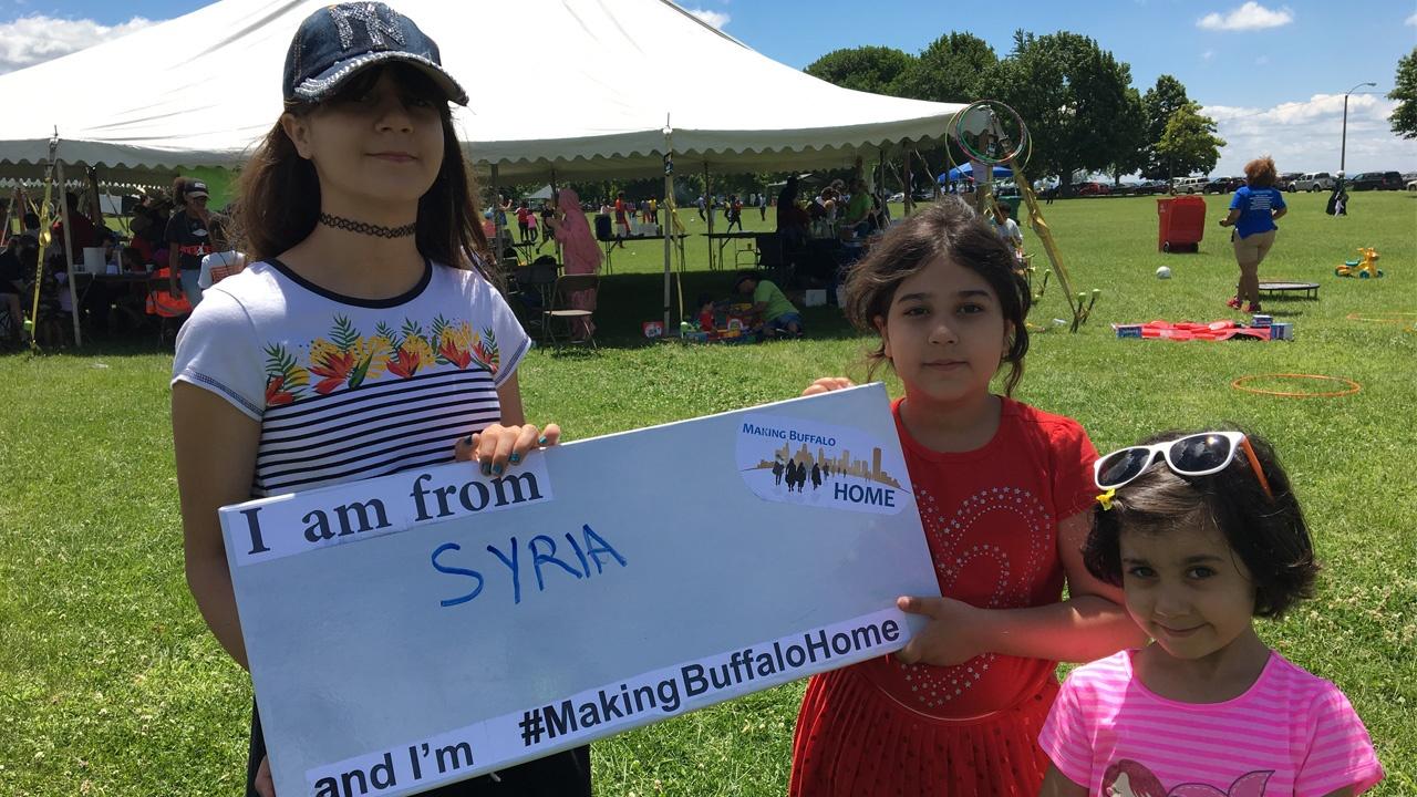 family from Syria holding a Making Buffalo Home sign