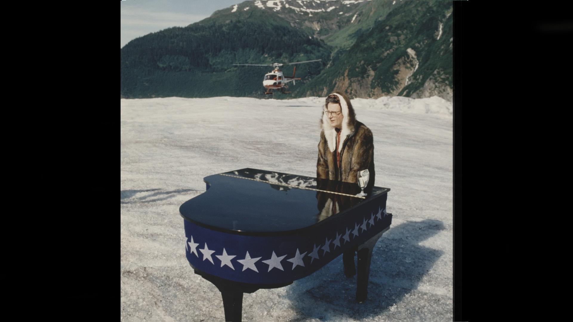 Mark Russell performing on top of the Mendenhall glacier in Alaska with his piano wearing a parka