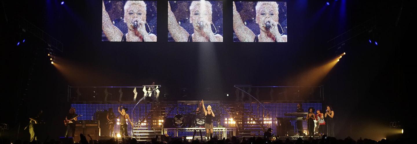 P!Nk performing onstage at Wembley in a black tank top with her arm raised in the air