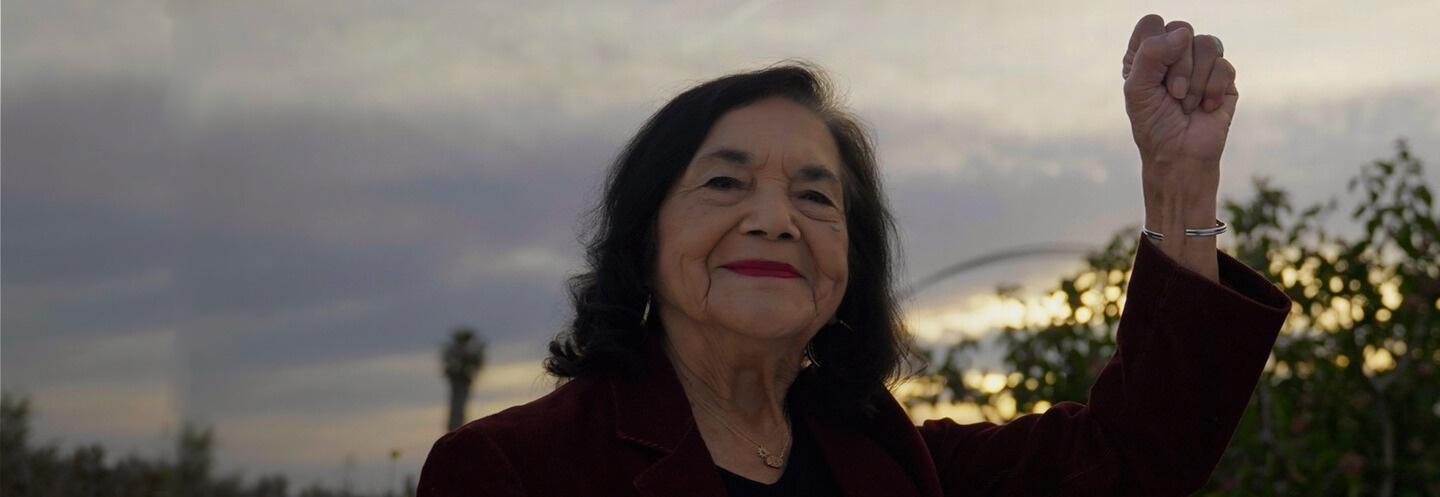 A Latina woman raising her fist in the air