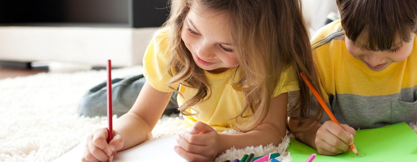 An image of a little girl and boy writing side-by-side