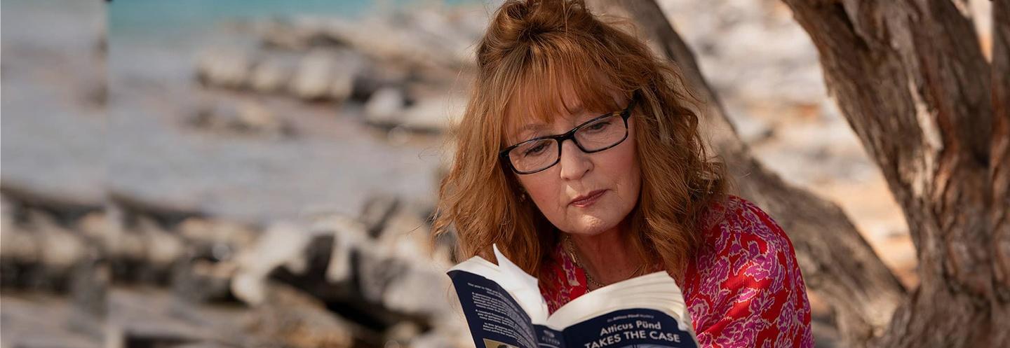 Woman with red hair and glasses reading a book