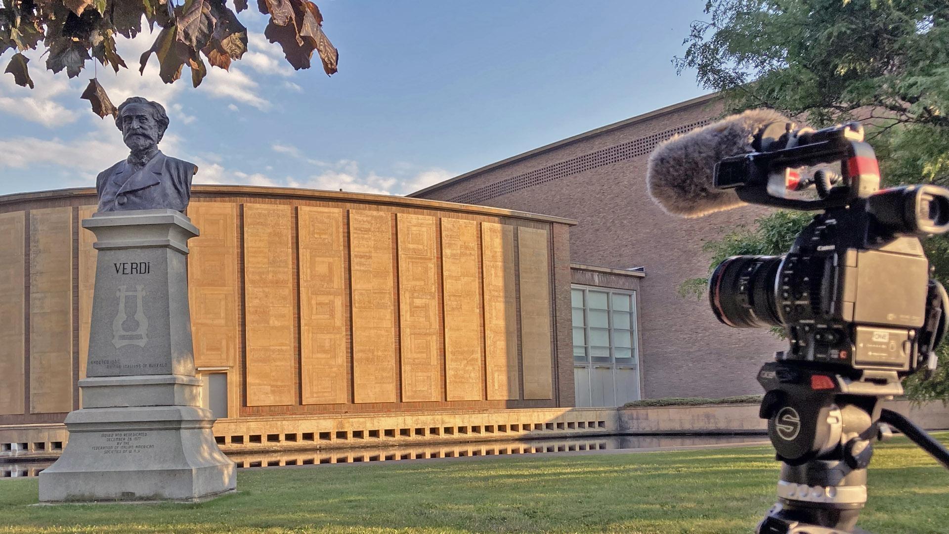 camera on tripod outside Kleinhans Music Hall with stature of Verdi