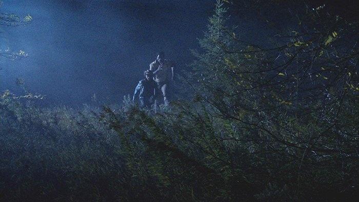 Still from the film: slaves running through trees and grass in a night escape.