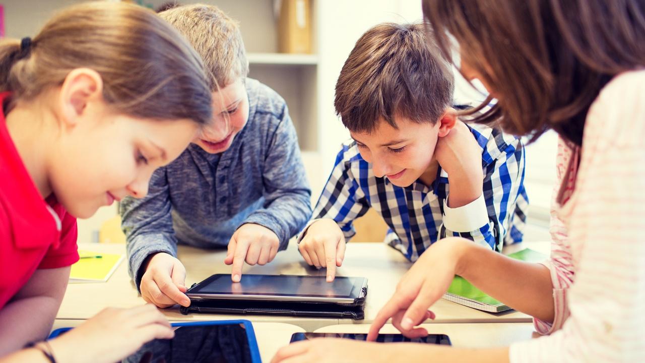 teacher and children in a classroom working on ipads