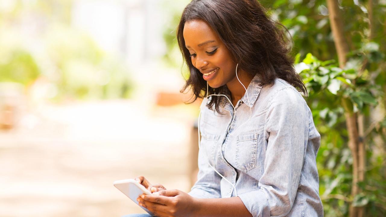 woman with earbuds in looking at phone