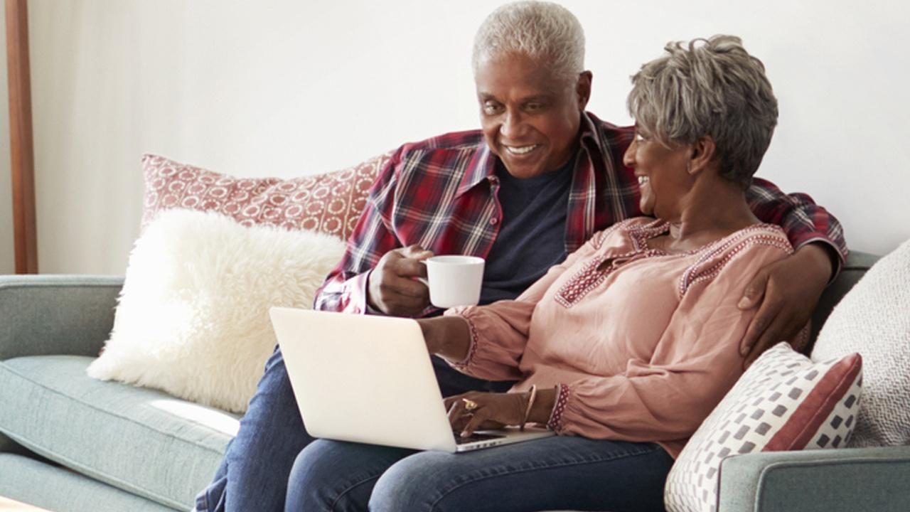 man and woman sitting on couch with laptop