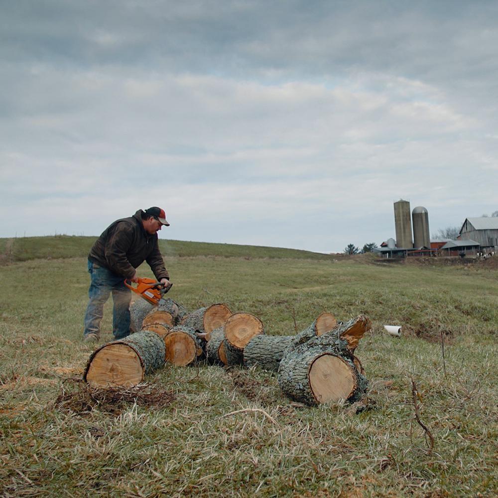 Dairy farmer, Jay Simeral saws wood at the backdrop of his Adena, Ohio farm.