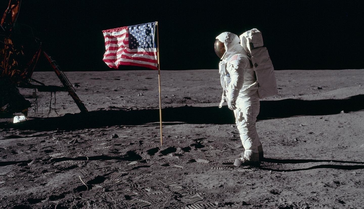 Astronaut Edwin E. Aldrin, Jr., Lunar Module Pilot of the first lunar landing mission, poses for a photograph beside the deployed United States flag during Apollo 11 extravehicular activity (EVA) on the lunar surface. The Lunar Module (LM) is on the left, and the footprints of the astronauts are clearly visible in the soil of the moon. Credit: NASA, July 20, 1969