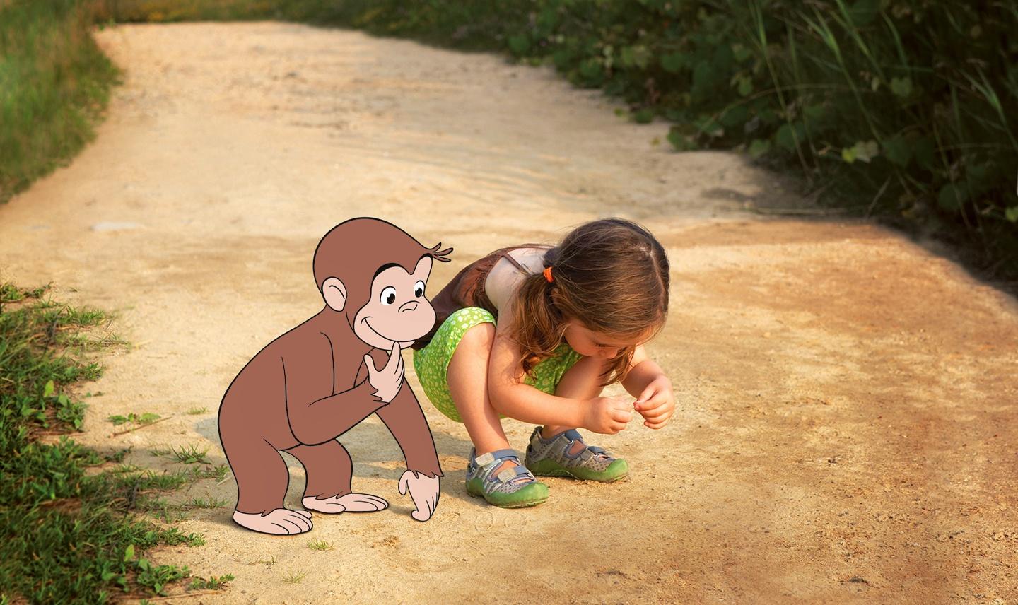 Curious George with youg girl looking at ground.