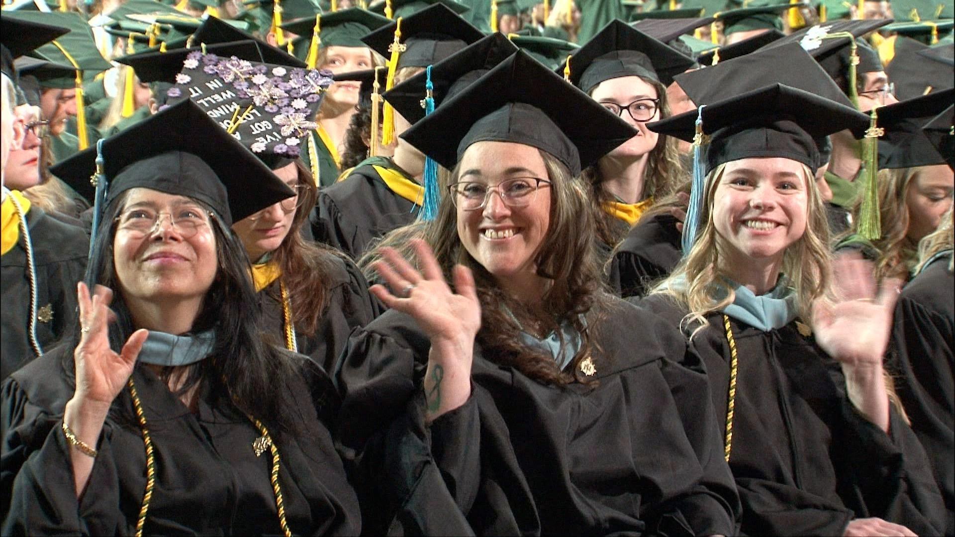 Graduates wave to the camera at NMU's commencement ceremony