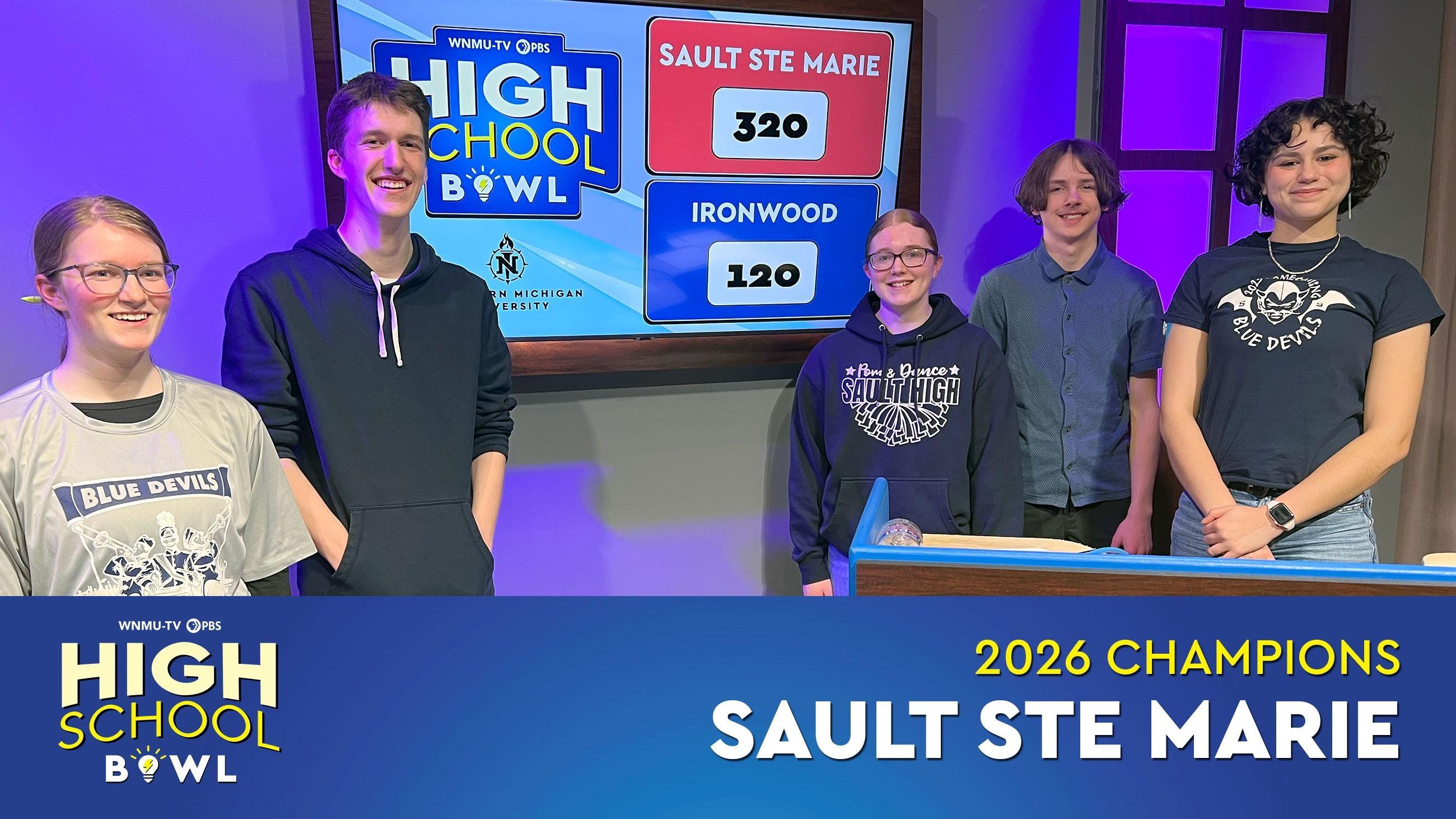 Sault Ste. Marie High School Bowl team standing in front of scoreboard showing their winning score after the championship match
