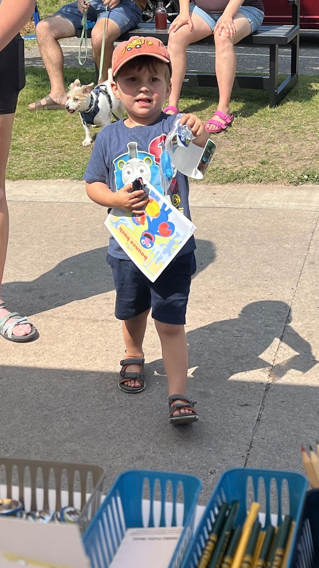 Young supporter holding PBS materials at a WNMU-TV community event.