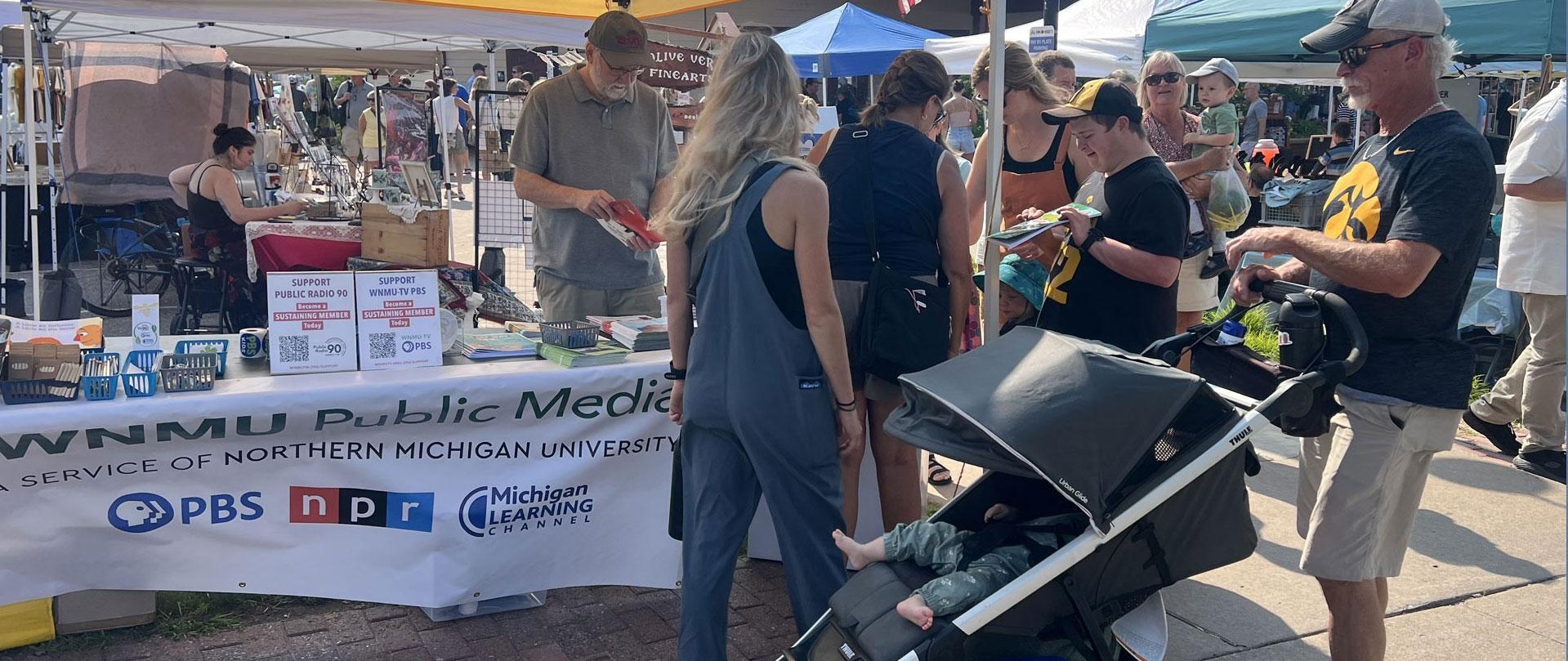 Families visit the WNMU Public Media booth during a Northern Michigan community event.